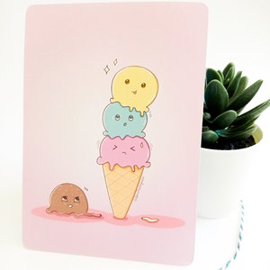 Pode incluir: Um cartão rosa apresenta um cone de sorvete de desenho animado com três bolas em amarelo, azul e rosa, cada uma com uma expressão diferente. Uma bola derretida está na parte inferior esquerda. O cone está em um fundo rosa, com uma pequena planta em um vaso branco à direita.