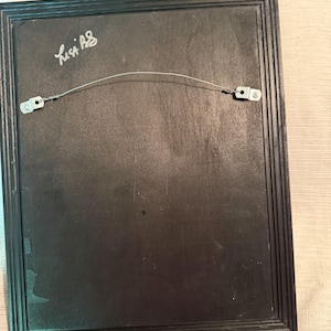 May include: Back of a framed artwork with a black wooden frame. A wire is strung across the back for hanging. The artist's signature, "Lisa AS", is visible in the upper left corner.