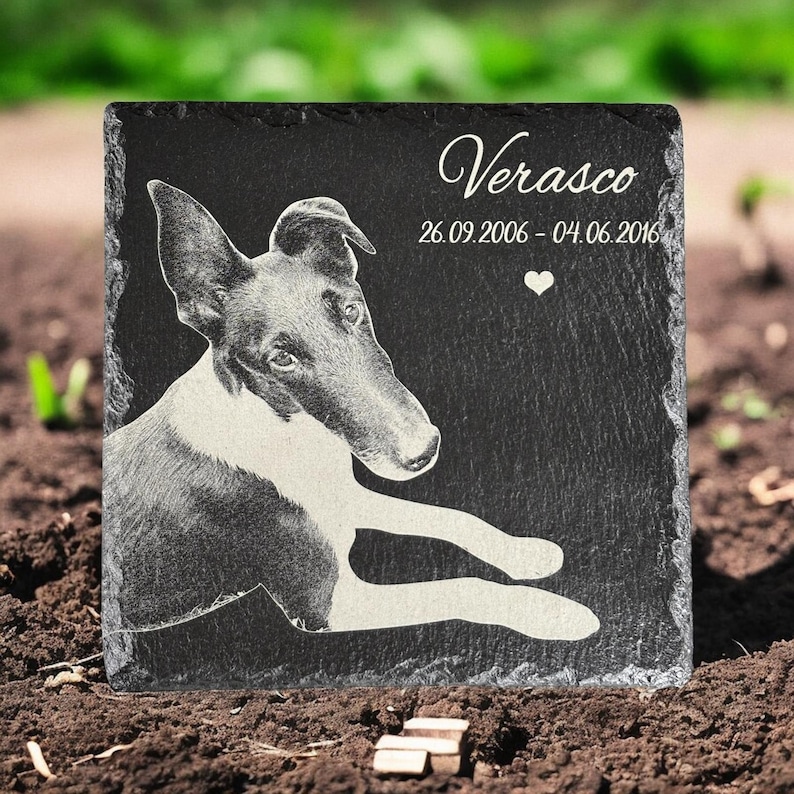 Puede incluir: Una placa conmemorativa para mascotas de pizarra negra con una imagen grabada de un perro. El perro est&aacute; tumbado con la cabeza girada. El nombre "Verasco" y las fechas 26.09.2006 - 04.06.2016 est&aacute;n inscritos, junto a un coraz&oacute;n.