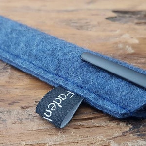 Könnte beinhalten: Ein blaues Filz-Stift-Etui mit einem schwarzen Stift darin und einem schwarzen Etikett mit der Aufschrift "Faden".