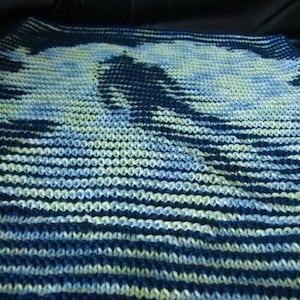 May include: A knitted throw blanket with a blue, white, and green striped pattern. The blanket is made of soft yarn and has a textured surface.