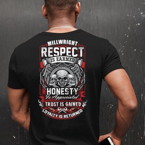 Op de afbeelding: Zwart T-shirt met een rood en wit grafisch ontwerp met de tekst "Millwright Respect is Earned Honesty is Appreciated Trust is Gained Loyalty is Returned". De grafiek bevat ook drie schedels met vleugels en een ketting.