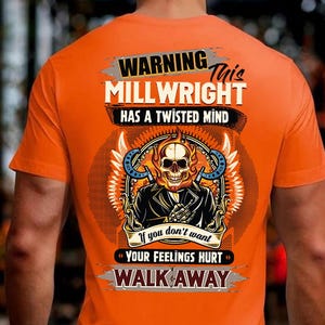 May include: Orange t-shirt with a graphic on the back. The graphic features a flaming skull wearing a jacket, surrounded by wings and horseshoes. Text reads "WARNING MILLWRIGHT HAS A TWISTED MIND" and "If you don't want YOUR FEELINGS HURT WALK AWAY."