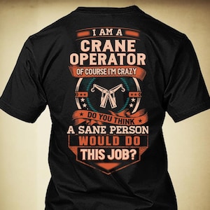 May include: Black t-shirt with the text "I AM A CRANE OPERATOR OF COURSE I'M CRAZY" in orange and white. The shirt features a crane graphic and the question, "DO YOU THINK A SANE PERSON WOULD DO THIS JOB?"
