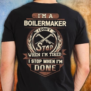 May include: Black t-shirt featuring the text "I'M A BOILERMAKER I DON'T STOP WHEN I'M TIRED I STOP WHEN I'M DONE" in brown and beige. The design includes crossed tools and flame accents.