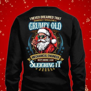 May include: Black sweatshirt featuring a graphic of Santa Claus wearing sunglasses and holding a pipe. Text reads "I NEVER DREAMED THAT SOMEDAY I WOULD BE A GRUMPY OLD MECHANICAL ENGINEER BUT HERE I AM SLEIGHING IT."