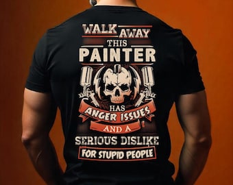 May include: A black t-shirt featuring a graphic on the back with a skull, two paint spray guns, and the text: WALK AWAY THIS PAINTER HAS ANGER ISSUES AND A SERIOUS DISLIKE FOR STUPID PEOPLE. The design uses white, orange, and black colour tones.