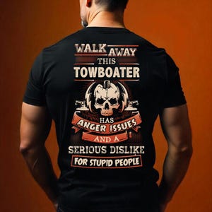 May include: Black t-shirt with a graphic design featuring a skull and the text "WALK AWAY THIS TOWBOATER HAS ANGER ISSUES AND A SERIOUS DISLIKE FOR STUPID PEOPLE". The design is in white, red, and orange.