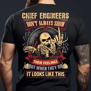 May include: Black t-shirt with a graphic featuring a skeleton giving the middle finger. Text reads "CHIEF ENGINEERS DON'T ALWAYS SHOW THEIR FEELINGS BUT WHEN THEY DO IT LOOKS LIKE THIS."