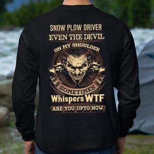 Puede incluir: Sudadera negra con un gráfico en la espalda. El gráfico presenta una cara de diablo con una quitanieves y el texto "SNOW PLOW DRIVER EVEN THE DEVIL ON MY SHOULDER SOMETIMES Whispers WTF ARE YOU UPTO NOW."