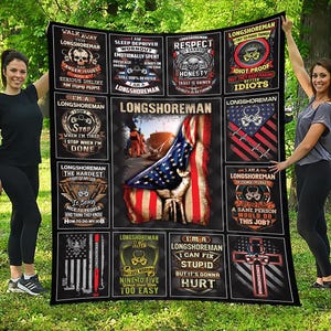 Könnte beinhalten: Eine schwarze Decke zum Thema Longshoreman mit verschiedenen Grafiken und Texten. Die Decke zeigt ein Design der amerikanischen Flagge, Totenköpfe und Sätze wie "Ich bin ein Longshoreman" und "Respekt wird verdient". Die Decke wird von zwei Personen gehalten.
