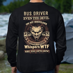 May include: Black sweatshirt with a graphic design on the back. The design features text that reads "BUS DRIVER EVEN THE DEVIL ON MY SHOULDER SOMETIMES Whispers WTF ARE YOU UPTO NOW" with a devil face and bus illustrations.