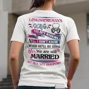 Puede incluir: Camiseta blanca con texto que dice "LONGSHOREMAN'S Wife YES.HE'S WORKING No, I DON'T KNOW WHEN HE'LL BE HOME Yes, We are still MARRIED No, HE'S NOT IMAGINARY". El texto es de varios colores y fuentes.