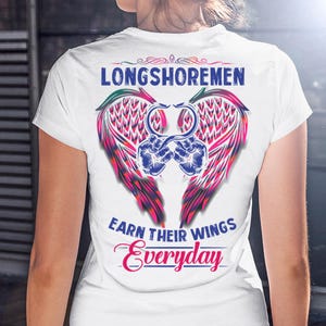 Puede incluir: Camiseta blanca con un gráfico colorido en la espalda. El gráfico presenta un par de puños azules, alas en tonos rosa, rojo y verde, y las palabras "LONGSHOREMEN" y "EARN THEIR WINGS Everyday".