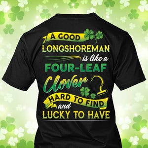 Puede incluir: Camiseta negra con temática del Día de San Patricio. La camiseta presenta texto en amarillo y verde que dice "A GOOD LONGSHOREMAN is like a FOUR-LEAF Clover HARD TO FIND and LUCKY TO HAVE". Incluye gráficos de tréboles.