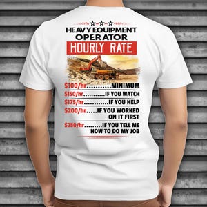 May include: White t-shirt with the text "HEAVY EQUIPMENT OPERATOR HOURLY RATE" in black and red. The shirt features an image of construction equipment. The hourly rates are listed below the image.