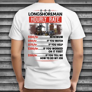 Puede incluir: Camiseta blanca con el texto "LONGSHOREMAN HOURLY RATE" en rojo y negro. La camiseta presenta una imagen de una carretilla elevadora y un camión. El texto incluye tarifas por hora y condiciones.