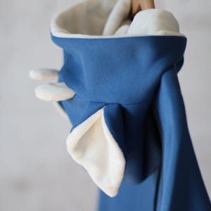 K&ouml;nnte beinhalten: Ein blauer Kapuzenpullover mit wei&szlig;em Fleece-Futter und Ohren an der Kapuze.