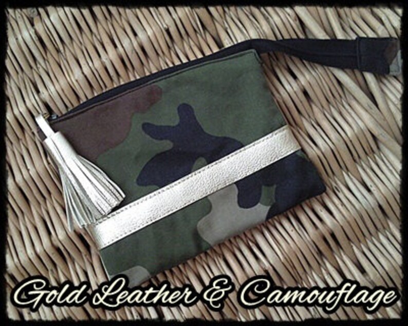 May include: A camouflage fabric pouch with a gold leather trim and a white tassel. The pouch has a zipper closure and a black strap.