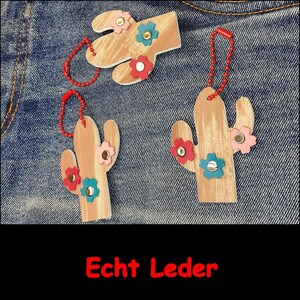 May include: Three light brown leather cactus-shaped ornaments with red, blue, and pink flower-shaped accents attached with metal rivets. Each cactus features a red ball chain loop for hanging. The text Echt Leder is printed in red at the bottom.