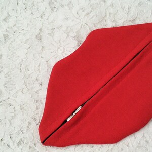 May include: A red zippered pouch shaped like a pair of lips.