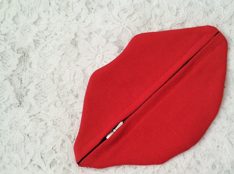 May include: A red zippered pouch shaped like a pair of lips.