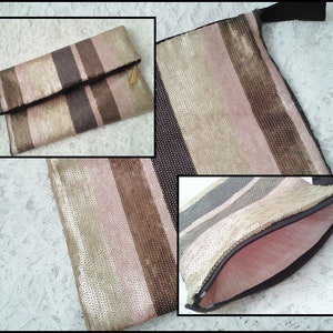May include: A gold and pink striped clutch with a zipper closure. The clutch is made of a sparkly material.