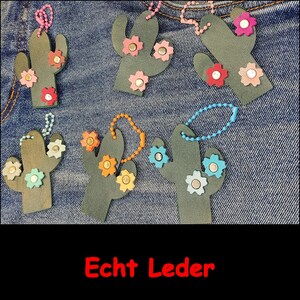 May include: Six dark green cactus-shaped leather keychains, each featuring colorful flower-shaped studs and a matching beaded ball chain. The text "Echt Leder" is printed in red at the bottom of the image, indicating genuine leather construction.