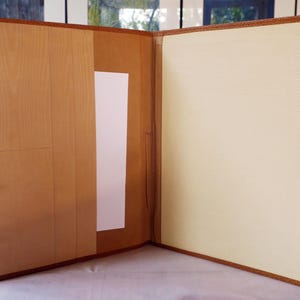 Puede incluir: Un portafolio de cuero marrón abierto, que revela un interior claro. El portafolio tiene un borde texturizado y un bolsillo en el lado izquierdo. Se inserta una hoja de papel blanca. El portafolio está vacío y listo para usar.