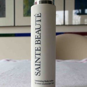 Könnte beinhalten: Eine weiße Flasche Sainte Beauté Luminizing Body Lotion für einen strahlenden Teint.