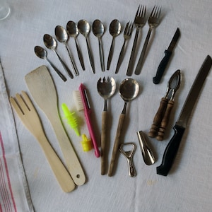 Könnte beinhalten: Eine Sammlung von Küchenutensilien, darunter Löffel, Gabeln, Spatel, ein Flaschenöffner, ein Nussknacker, ein Messer und eine Reinigungsbürste.