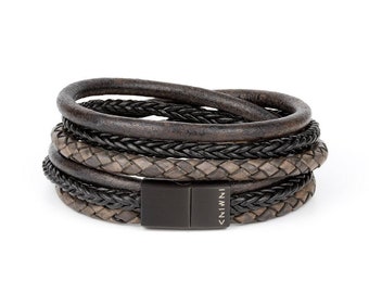May include: A multi-layered leather bracelet with a black metal clasp. The bracelet features a braided design in brown and black leather.