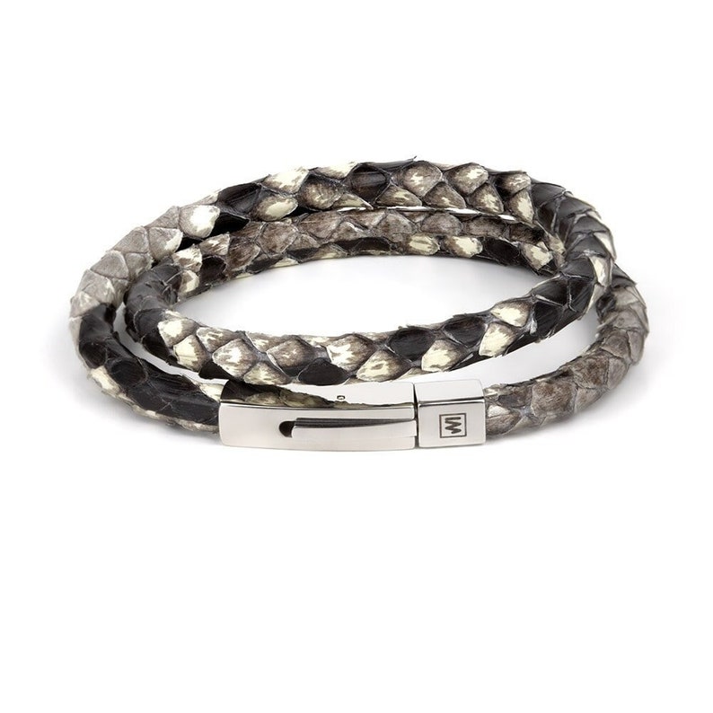 May include: A double-wrap bracelet made of black and white snakeskin with a silver clasp. The clasp has a small "W" engraved on it.