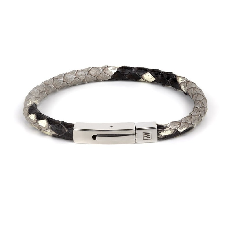May include: A grey and black braided leather bracelet with a silver clasp. The clasp has a small metal logo with the letter "W" on it.