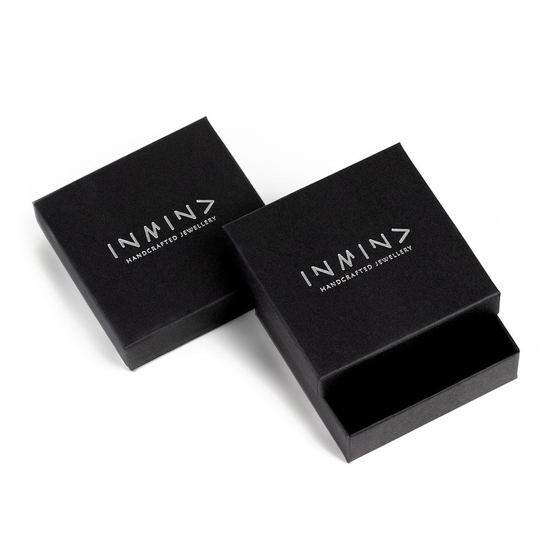 May include: Two black square boxes with the logo "INMN> HANDCRAFTED JEWELLERY" printed in silver on the top of each box.