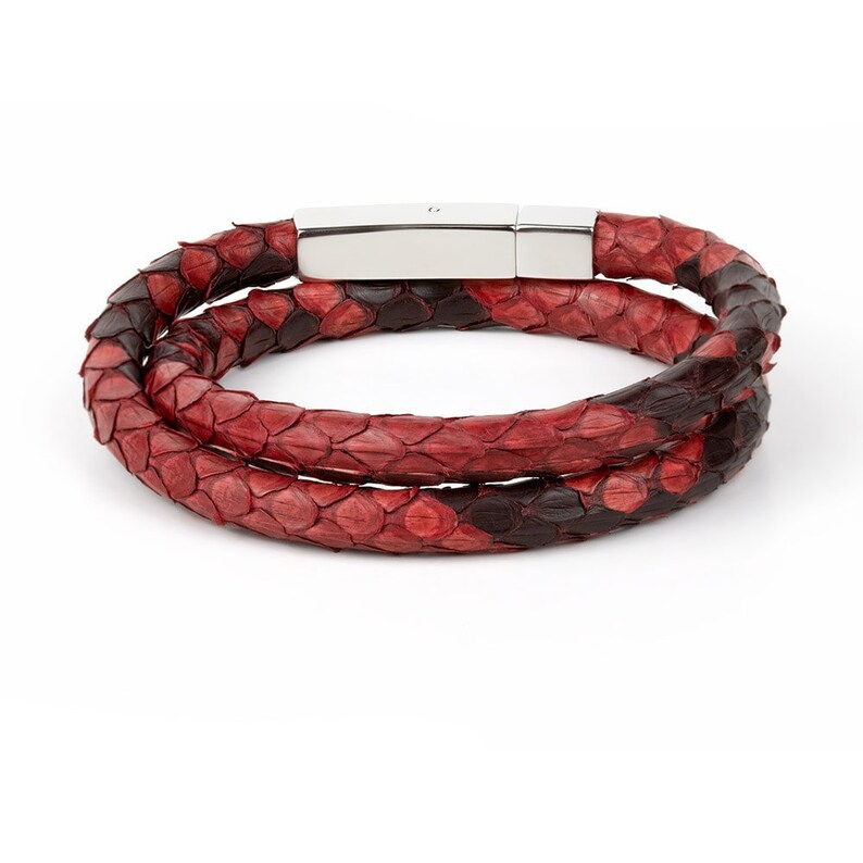 Puede incluir: Un brazalete de doble vuelta hecho de piel de serpiente roja y negra con un cierre magn&eacute;tico plateado.