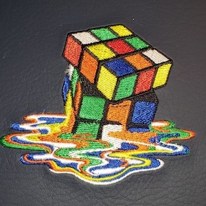 May include: A colorful embroidered patch of a Rubik's Cube melting into a puddle of rainbow-colored liquid.