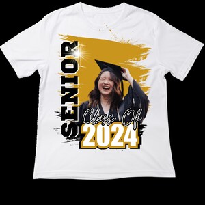 May include: White t-shirt featuring a graduation theme. The shirt has the word "SENIOR" printed vertically in black and white, with "Class Of 2024" in gold and white. A photo of a smiling graduate in a cap and gown is in the center.