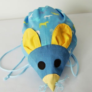 Könnte beinhalten: Eine blaue Kordeltasche in Form einer Maus mit gelben Ohren und einer gelben Nase. Die Tasche hat ein weiß-blaues Muster mit Pferden und anderen Tieren.