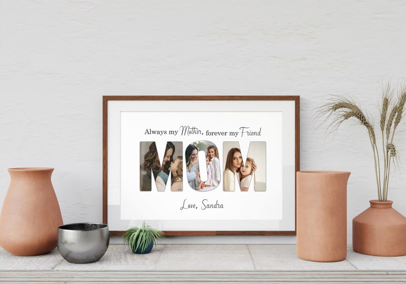 May include: A framed print with the word "MOM" spelled out with photos inside each letter. The text above reads "Always my Mother, forever my Friend" and below "Love, Sandra". The frame is brown and sits on a white surface.