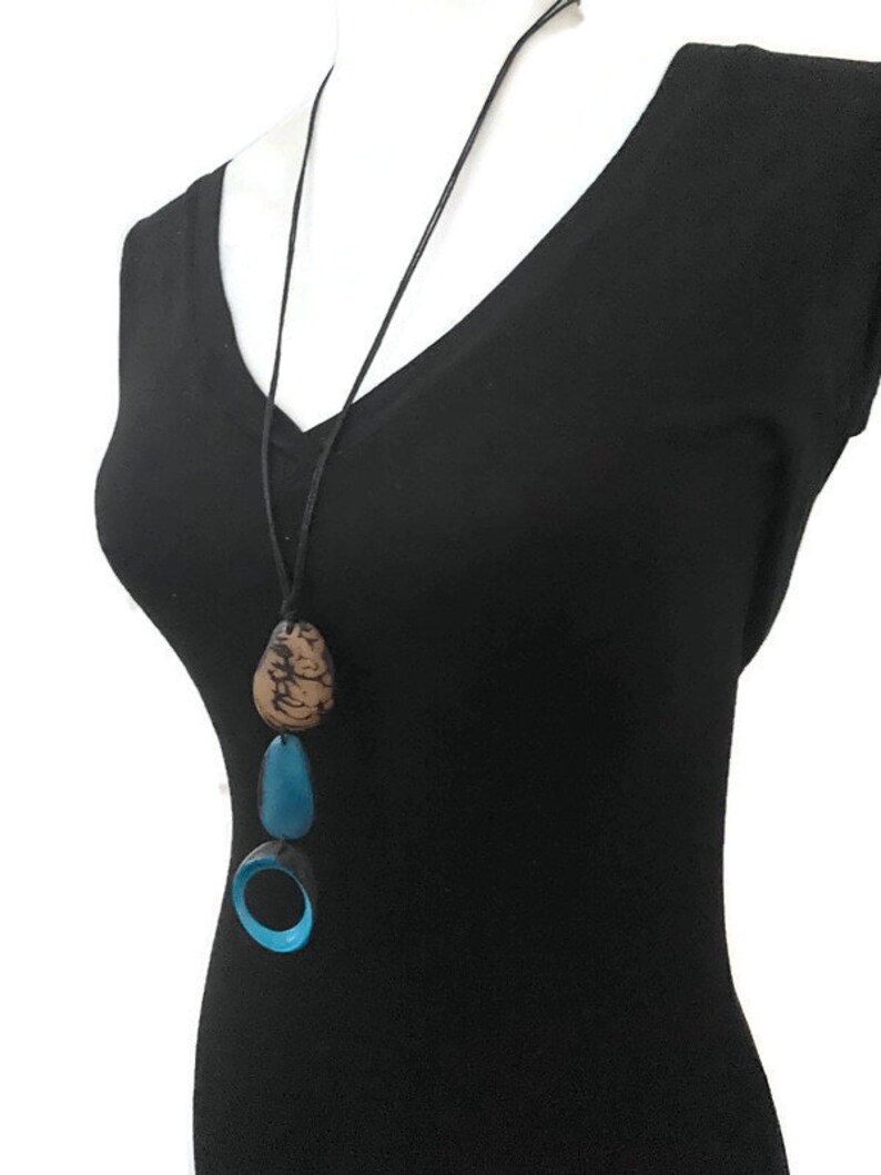 May include: A long black leather cord necklace with three turquoise and brown pendant charms. The charms are shaped like a circle, an oval, and a teardrop.