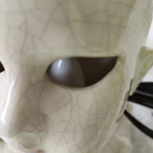 Puede incluir: Primer plano de una escultura de cer&aacute;mica de una cara con un ojo abierto. La escultura es de color blanquecino con un aspecto agrietado y envejecido. La cuenca del ojo es un vac&iacute;o oscuro y la oreja es visible en el lateral.