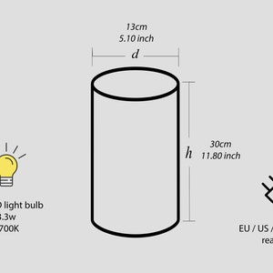 K&ouml;nnte beinhalten: Eine wei&szlig;e zylindrische Lampe mit schwarzem Umriss. Die Lampe ist 30 cm hoch und 13 cm im Durchmesser. Sie verwendet eine E14 LED-Gl&uuml;hbirne mit einer Leistung von 3,3 W und einer Farbtemperatur von 2700 K. Die Lampe ist kompatibel mit EU-, US-, UK- und AU-Steckdosen.