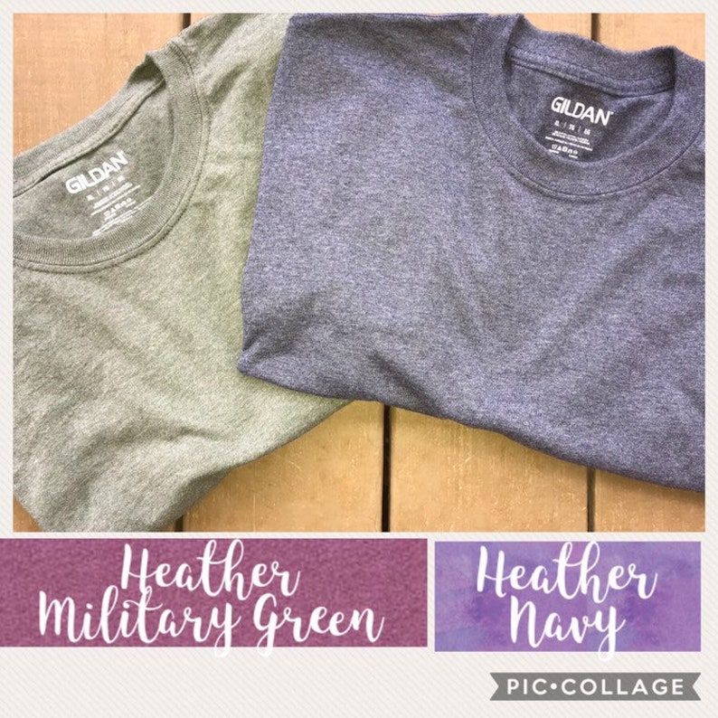 May include: Two Gildan brand t-shirts, one in heather military green and one in heather navy. The shirts are folded and laid out on a wooden surface.