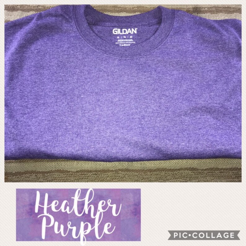 May include: A heather purple Gildan t-shirt. The shirt is folded and laid flat on a brown surface.