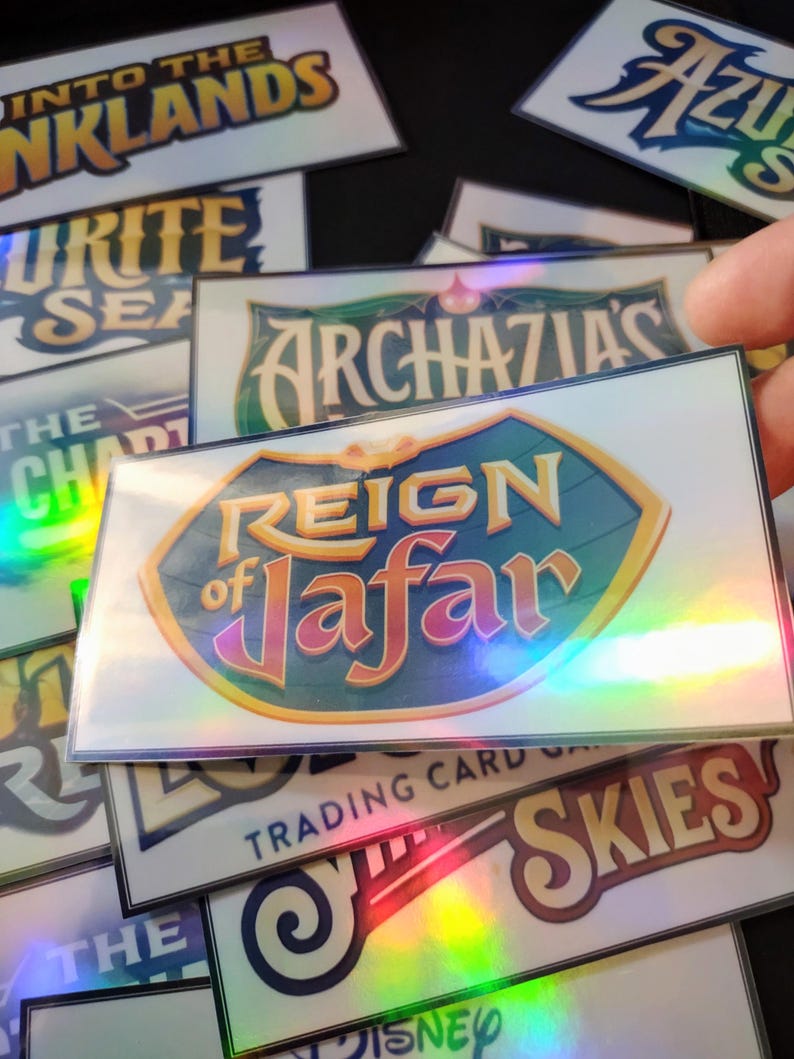 May include: A collection of holographic trading cards featuring various Disney characters and themes, including "Reign of Jafar", "The Archazias", "Into the Inklands", "Sky's the Limit", and "The Pirate Sea".