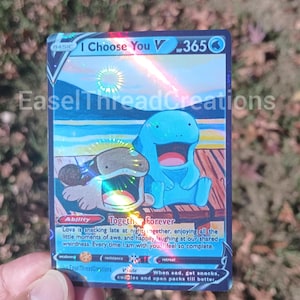 May include: A holographic trading card featuring two cartoon characters, one blue and one tan, with the text "I Choose You V". The card has a blue and white background with the text "Together Forever".