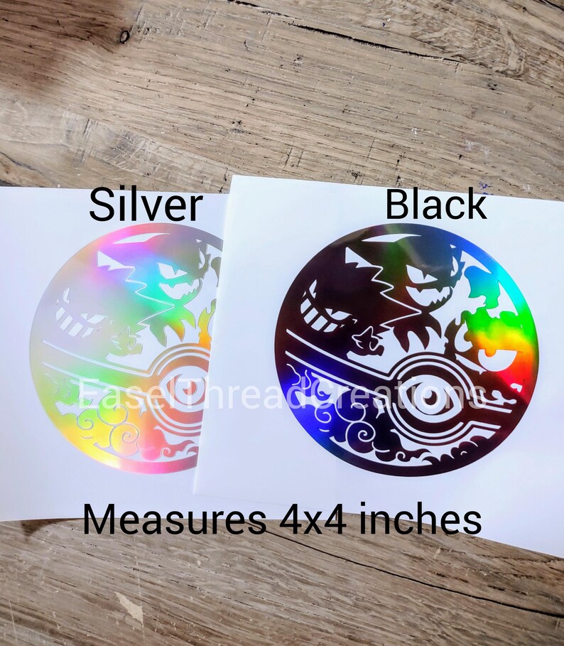 May include: Two 4x4 inch vinyl stickers featuring a black and white silhouette of a Pokemon character against a holographic background. The stickers are available in silver and black.