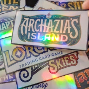 May include: A stack of holographic trading cards featuring various game titles, including "Lorcana Trading Card Game", "Archazia's Island", and "The Disney Lorcana".