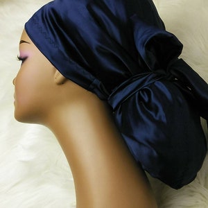 May include: A navy blue satin sleep cap with a bow tied on top. The cap is designed to protect hair while sleeping.